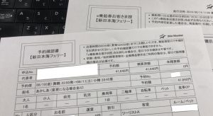 黒いコンピューターのキーボードの横の机の上にある日本のフェリーの予約フォームのクローズアップ。.