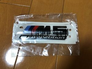 透明な包装に入った M5 競技用車両用デカールのシートが木製の床に貼られています。.