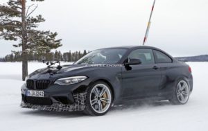 地面には雪が積もり、背景には木々が見える、雪道を走る黒いスポーツカー。.