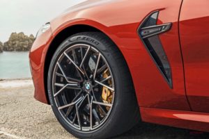 海辺にある赤い BMW スポーツカーの前輪とフェンダーのクローズアップ。.