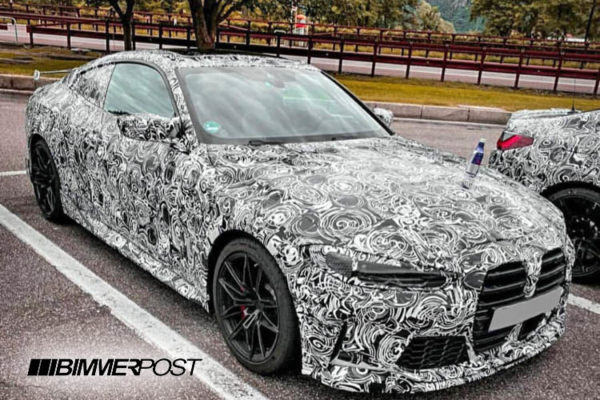 白黒の渦巻き模様で覆われたカモフラージュされたBMWのテストカーが外に駐車されています。.