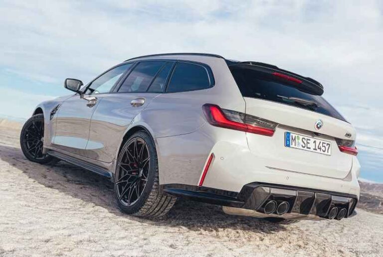 曇り空の下、砂地に駐車された白い BMW M3 ツーリング スポーツ ワゴン。.