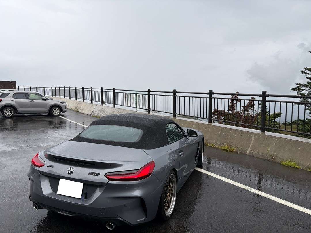 雨に濡れた展望駐車場に停められた灰色のBMWコンバーチブル