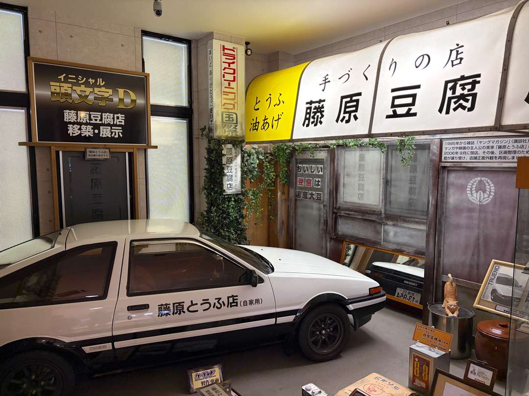 『頭文字D』に登場する藤原豆腐店の店舗外観と、藤原とうふ店と書かれた白い車の展示