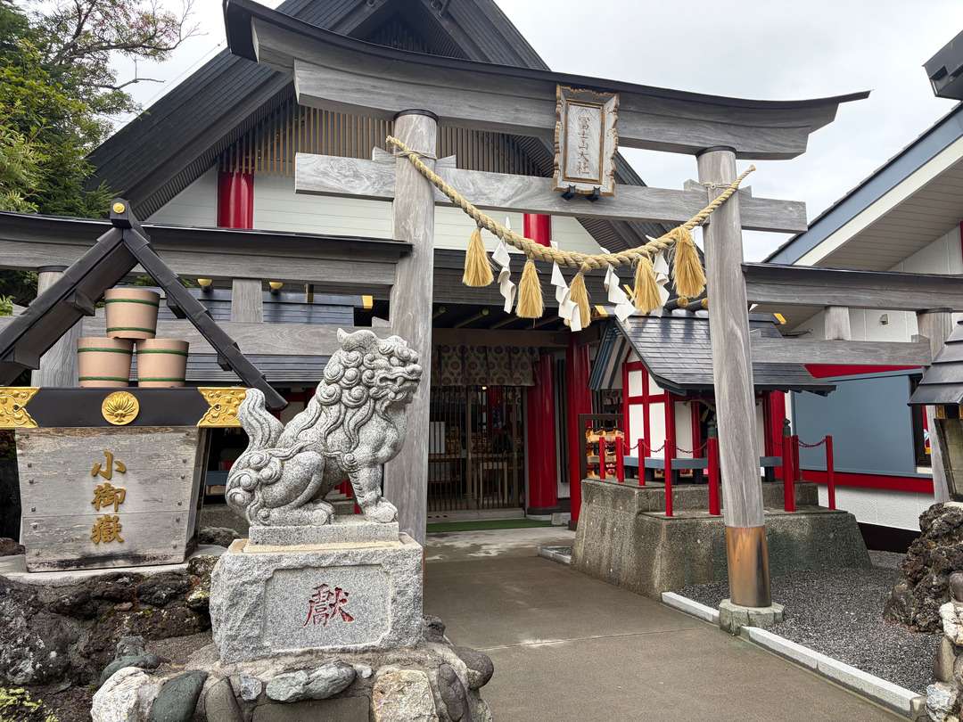 しめ縄が掛けられた鳥居と狛犬のある神社の社殿正面。
