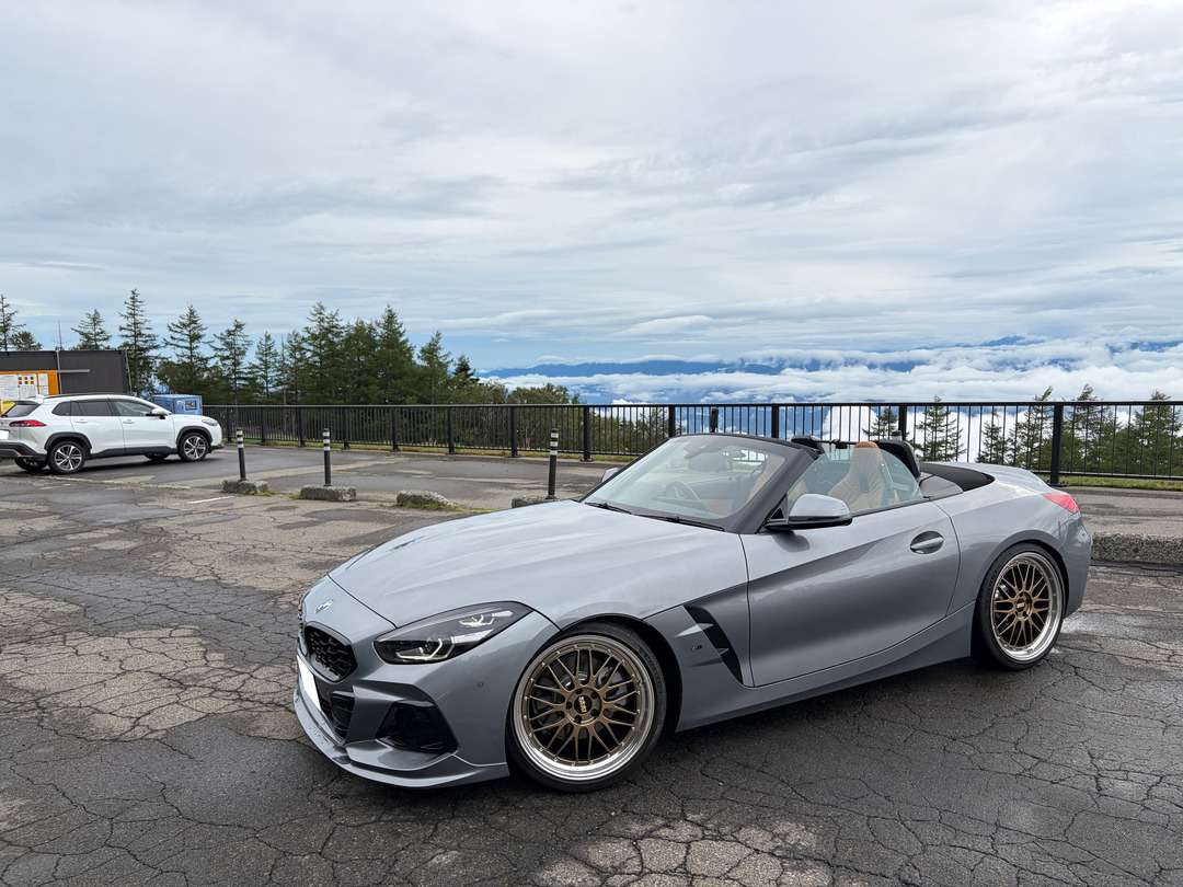 山の景色を望む駐車場に停められた、グレーのオープンカー BMW Z4。