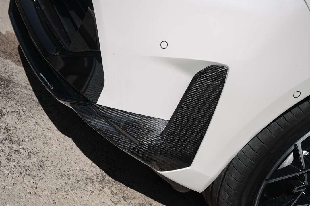 白いスポーツカーのホイール付近に装着された黒いカーボン製エアロパーツ