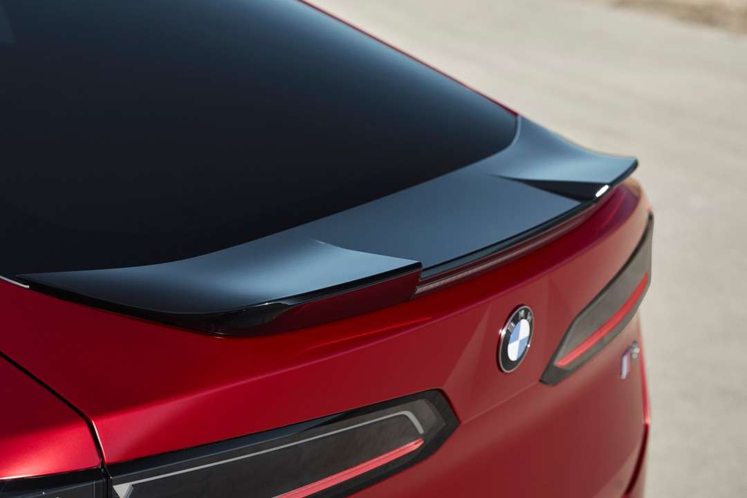 赤いBMW車の後部に取り付けられた黒いリアスポイラーとテールライト、BMWエンブレム】【。