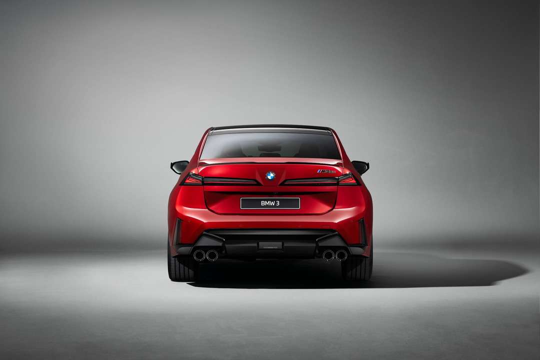 赤いBMW 3シリーズの後ろ姿。灰色のスタジオ背景で、左右2本ずつのマフラーが見える。