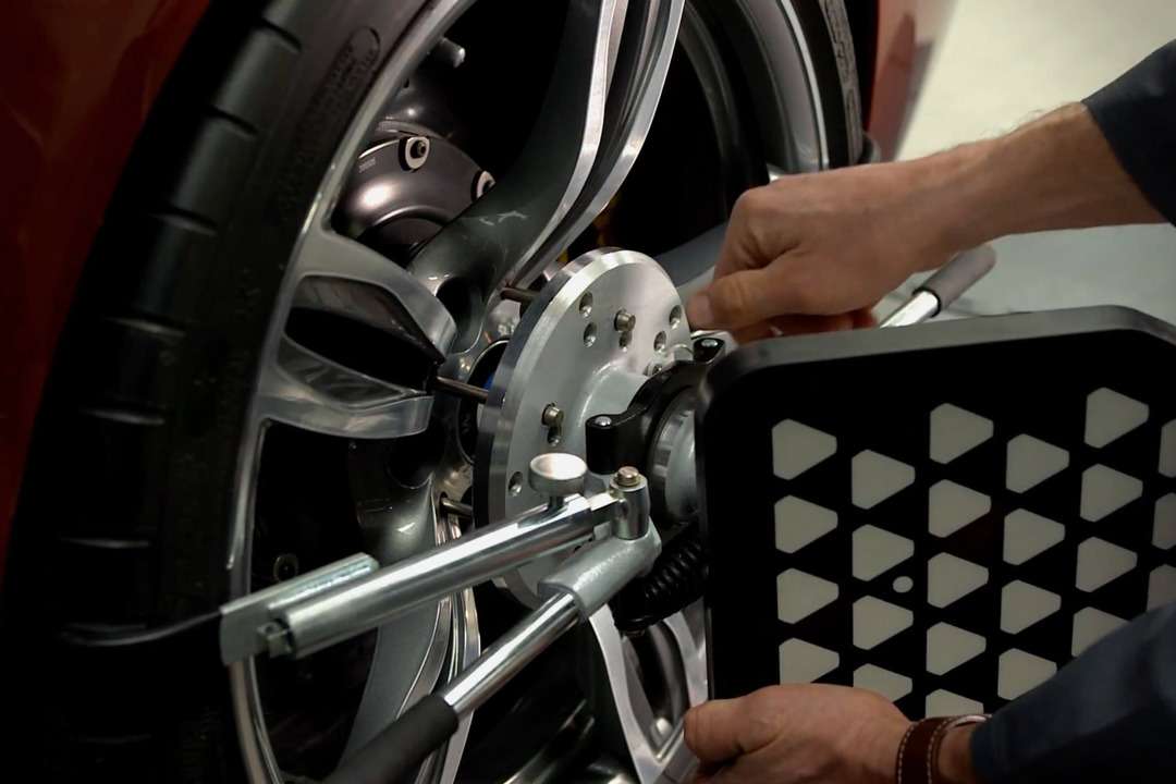 自動車のホイールに測定器具を取り付ける整備作業員の手元